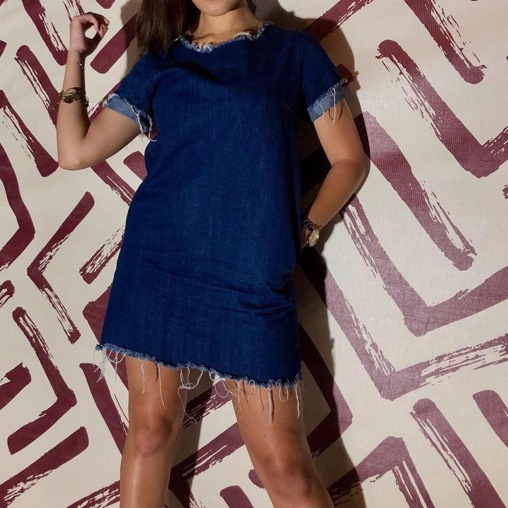 Blue denim dress with frayed edges, short sleeves, pockets, and a raw hem.